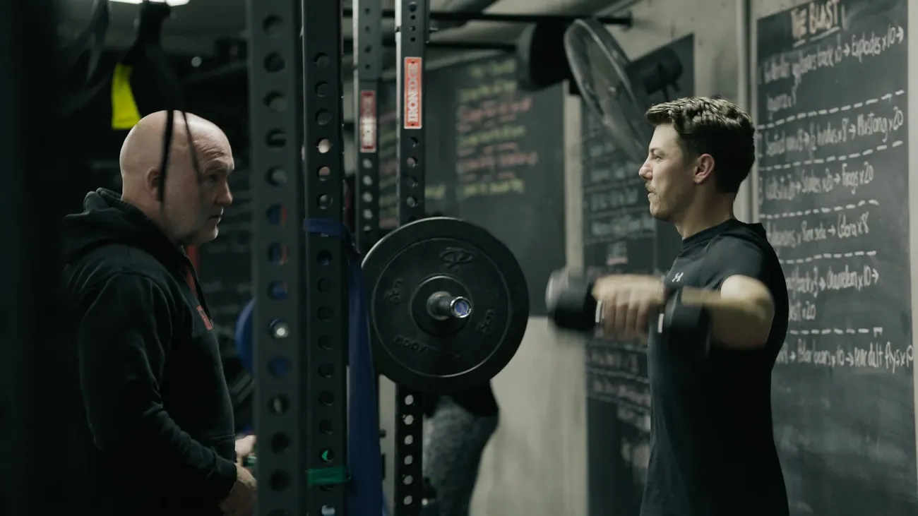 Mick Mackell coaching a member through a dumbbell raise
